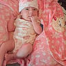 Athena is registered to the contest to win money with this photo: baby, infant, child, portrait, lying_down, blanket, pink, floral, hat, onesie, smiling, face, hand, fist, couch, pillow, indoor, cozy, textile, photography