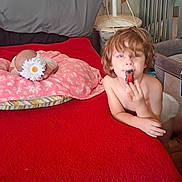 Alixx joined the competition — help win amazing prizes! child, toddler, indoors, bedroom, bed, red_blanket, pillow, flower, snack, eating, messy_hair, portrait, sitting, lying_down, crib, fan, furniture, wall, home, candid