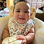 Angel is registered to the contest to win money with this photo: baby, bib, child, container, cute, decor, expression, face, food, hand, happy, high_chair, home, indoor, infant, person, plush, sitting, smiling, young_child