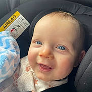 Luca is registered to the contest to win money with this photo: baby, blue_eyes, car_seat, child, blanket, smile, infant, cute, seatbelt, clothing, face, closeup, happy, indoor, safety, head, skin, person, young_child, comfort
