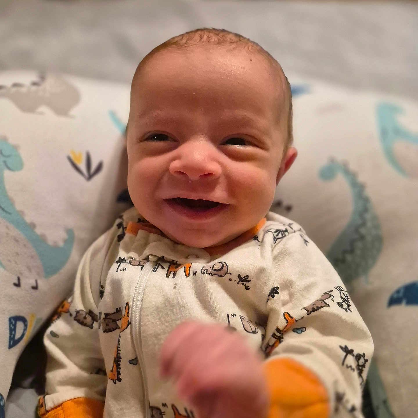 Merritt joined the competition — help win amazing prizes! baby, child, comfort, cozy, cute, dinosaur_pillow, expression, face, hand, happy, indoors, infant, onesie, patterned_clothing, portrait, sleepwear, smiling, soft, young_child, zipped_clothing