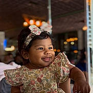 Dashly is registered to the contest to win money with this photo: baby, bokeh, cheeks, child, cute, expression, face, fashion, floral_dress, girl, hand, happy, headband, indoors, infant, joy, person, portrait, smile, warm_lighting