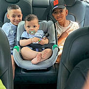 Jassim participe au concours pour gagner de l'argent avec cette photo : child, baby, car_seat, car_interior, smile, peace_sign, pacifier, seatbelt, hat, short_hair, tshirt, sitting, happy, family, brothers, indoors, casual_clothing, transportation, bonding, cute