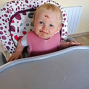 Louise participe au concours pour gagner de l'argent avec cette photo : baby, baby_clothing, blond_hair, blue_eyes, child, chocolate, curious, cute, face, feeding, floor_tiles, high_chair, indoor, infant, messy, pink_bib, plastic_tray, portrait, smile, toddler