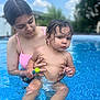 child, toddler, woman, pool, water, swimsuit, outdoor, summer, toy, wet_hair, baby, holding, blue_sky, clouds, nature, skin, expression, person, family, recreation