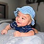baby, child, smile, hat, denim_hat, striped_shirt, blue_shirt, blanket, indoor, face, happy, cute, infant, person, skin, portrait, lying_down, soft_texture, cozy, young