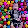 baby, child, smiling, ball_pit, colorful, plastic_balls, striped_clothing, socks, hand, play, indoor, cute, infant, happy, person, portrait, toy, fun, bright, leisure