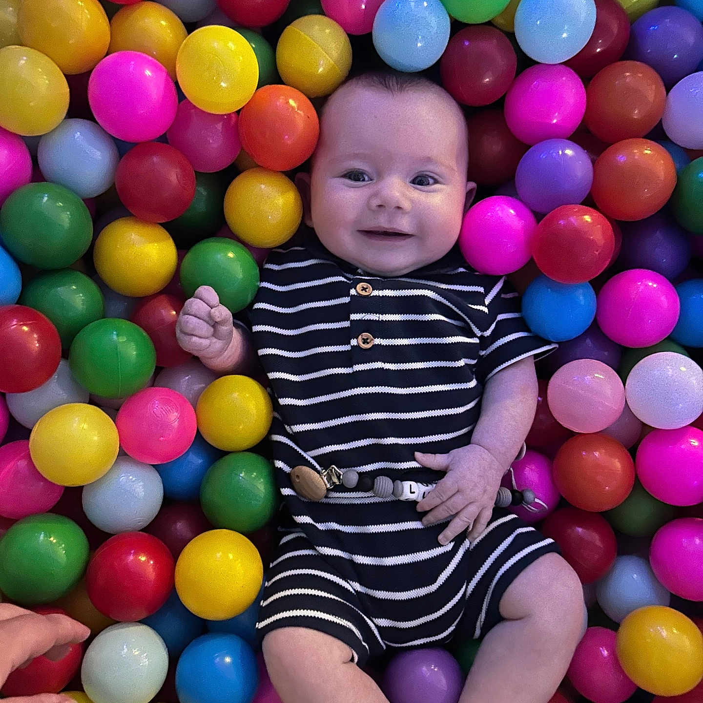 Lukasz is registered to the contest to win money with this photo: baby, ball_pit, bright, child, colorful, cute, fun, hand, happy, indoor, infant, leisure, person, plastic_balls, play, portrait, smiling, socks, striped_clothing, toy