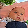 baby, child, pink_hat, outdoor, sunhat, face, blue_eyes, arm, person, nature, green_leaves, sky, daylight, holding, cute, infant, polka_dot_clothing, closeup, portrait, expression