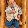baby, infant, pacifier, vest, striped_shirt, jeans, socks, cushioned_seat, mustard_color, curious_expression, indoor, young_child, clothing, portrait, relaxed, casual, hands, face, head, comfort