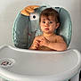 Juliette participe au concours pour gagner de l'argent avec cette photo : baby, child, childcare, clothing, expression, face, foot, furniture, hair, hand, high_chair, indoor, looking, person, room, seat, sitting, skin, table, toddler
