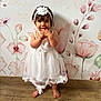 baby, barefoot, child, cute, fashion, floral_wallpaper, happy, headband, indoor, innocent, person, playful, portrait, small, smiling, standing, toddler, white_dress, wooden_floor, young_child