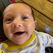 Malakai is registered to the contest to win money with this photo: baby, infant, smile, face, closeup, eyes, clothing, yellow_trim, animal_prints, pacifier, wooden_background, happy, cute, child, person, portrait, young, skin, mouth_open, indoors