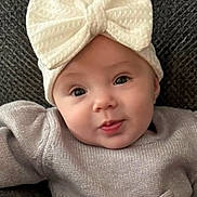 Natalie joined the competition — help win amazing prizes! baby, infant, child, headband, bow, knitwear, sweater, cute, face, portrait, smile, eyes, skin, expression, cozy, warm_clothing, indoor, texture, background, soft_lighting