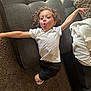 Anthony joined the competition — help win amazing prizes! child, curly_hair, white_tshirt, black_shorts, couch, carpet, blanket, pillow, indoor, playful, funny_face, tongue_out, relaxed, home, casual_clothing, person, smiling, light_shadows, living_room, stretching