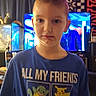 child, boy, portrait, standing, indoors, pokemon, t_shirt, smiling, serious_expression, short_hair, face, person, television, plush_toys, neon_light, aquarium, blue_shirt, home, wood_paneling, photograph