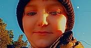 Tanner is registered to the contest to win money with this photo: beanie, blue_sky, child, closeup, clothing, eyes, face, fashion, hat, jacket, outdoor, person, portrait, puffer_jacket, selfie, smile, star_effects, sunlight, trees, winter
