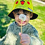 child, boy, hat, pikachu, yellow, dandelion, flower, hand, smile, outdoor, nature, grass, green, sunlight, portrait, casual_clothing, young, cute, playful, happy