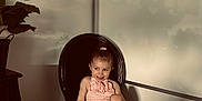 Milie participe au concours pour gagner de l'argent avec cette photo : toddler, child, smile, pink_dress, black_chair, indoor, plant, painting, silhouette, shadow, wall, hair_tie, barefoot, furniture, room, portrait, happy, cute, sitting, home