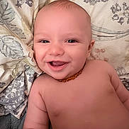 Jeremiah joined the competition — help win amazing prizes! baby, smiling, face, skin, necklace, blanket, pattern, floral, happy, infant, child, cute, lying_down, portrait, indoors, closeup, head, torso, chubby, joyful