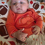 Lukas is registered to the contest to win money with this photo: baby, infant, child, portrait, orange_outfit, pumpkin, autumn, blanket, lying_down, face, eyes, hands, serious_expression, indoors, cozy, textile, patterned_blanket, closeup, photography, safe