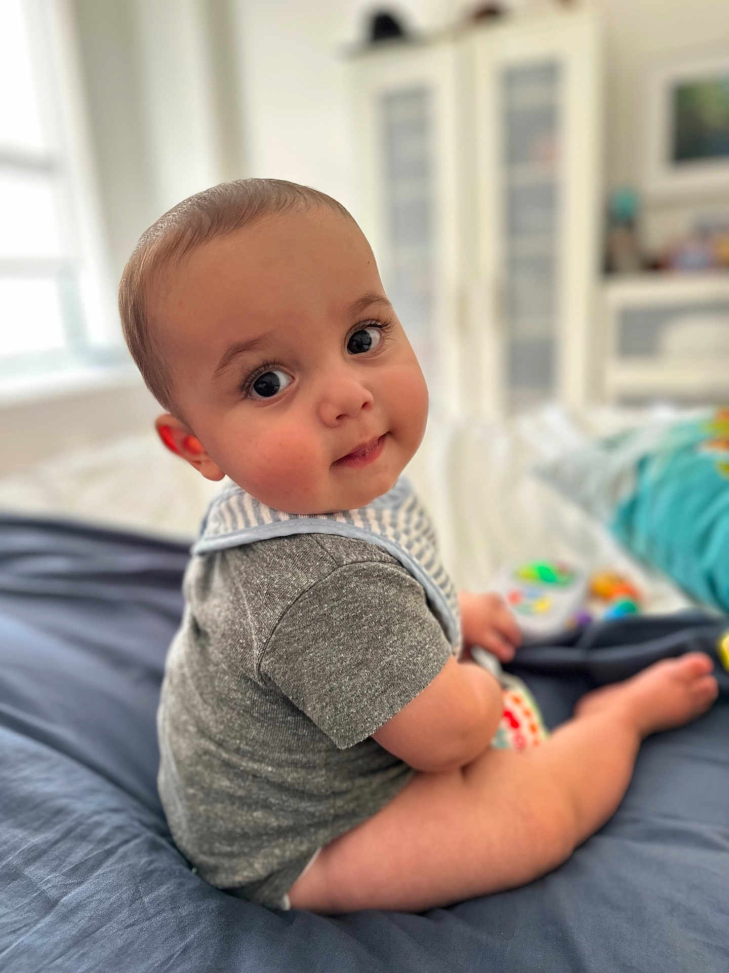 Shir is registered to the contest to win money with this photo: baby, bed, blanket, cheeks, child, cute, eyes, face, furniture, home, indoor, infant, onesie, person, portrait, sitting, skin, smile, toy, young