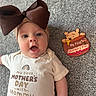 Elianna is registered to the contest to win money with this photo: baby, infant, headband, bow, onesie, text, carpet, floor, winnie_the_pooh, toy, celebration, mother's_day, cute, child, person, portrait, smiling, indoors, happy, lying_down