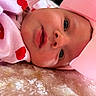 baby, infant, closeup, face, pink_bow, pink_clothing, hearts_pattern, blanket, soft_texture, cute, newborn, child, lying_down, portrait, adorable, skin, headgear, expression, young, cozy