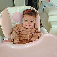Lily-Rose participe au concours pour gagner de l'argent avec cette photo : baby, child, high_chair, smile, curly_hair, headband, pink, happy, indoor, furniture, clothing, infant, cute, person, portrait, seat, playful, toddler, cheerful, hands