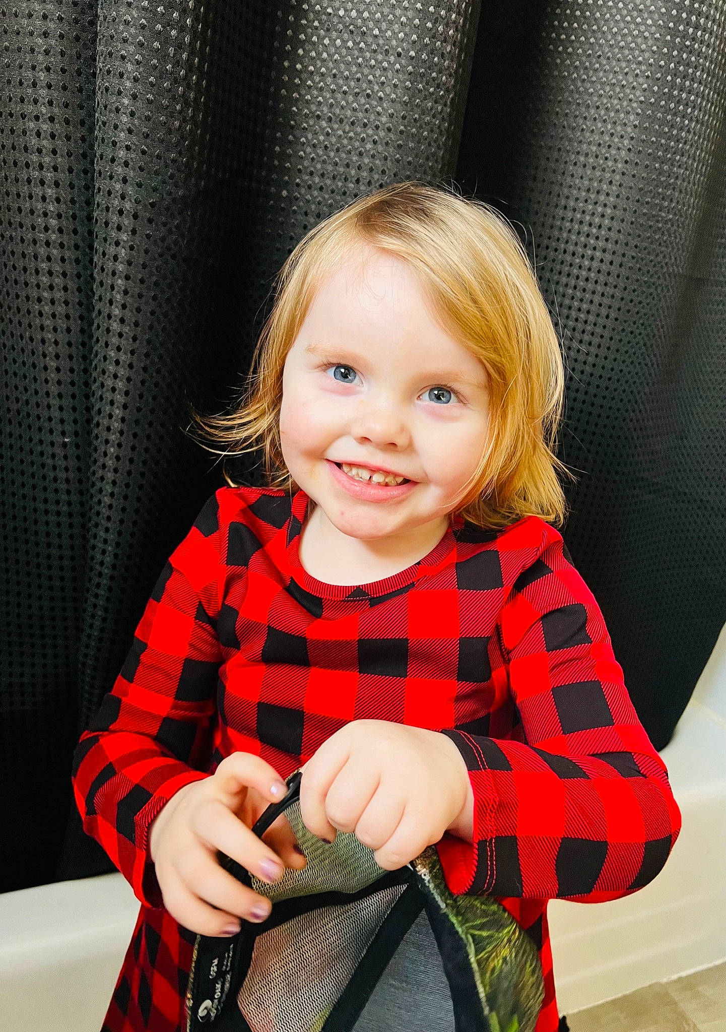 Raelyn joined the competition — help win amazing prizes! baby_products, baby_toddler_clothing, blond, chair, child, couch, event, fun, happy, joy, pattern, person, plaid, portrait_photography, room, sitting, sleeve, smile, sock, tartan