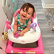 Lily is registered to the contest to win money with this photo: baby, child, walker, toy, indoor, flooring, smile, playful, person, happy, clothing, hair, face, baby_toy, pink, white, green, furniture, carpet, gate