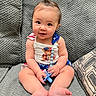 Lily joined the competition — help win amazing prizes! baby, infant, child, cute, pacifier, ponytail, couch, gray, textured, clothing, smiling, sitting, indoors, happy, face, hands, feet, person, portrait, young