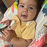 baby, infant, child, blue_eyes, yellow_shirt, lion_graphic, baby_seat, bright_starts, hands, curly_hair, cute, indoors, colorful, soft_toys, closeup, portrait, happy, chubby_cheeks, exploring, clothing