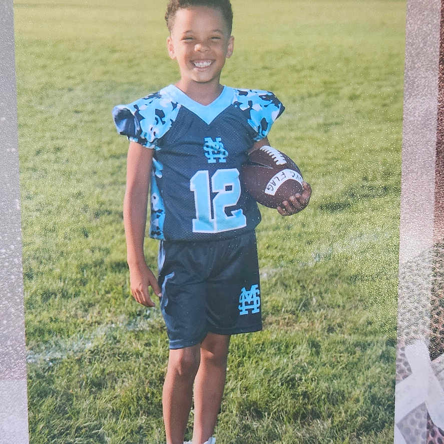 Lajack is registered to the contest to win money with this photo: ball, boy, child, clothing, face, football, footwear, grass, head, person, photography, plant, portrait, shirt, shoe, shorts, soccer, soccerball, sport, t_shirt