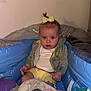 Rain is registered to the contest to win money with this photo: baby, child, yellow_bow, plush_toys, inflatable_pool, gray_jacket, white_shirt, yellow_shorts, indoor, light_skin, curly_hair, seated, toys, stuffed_animals, blue_pool, pink_toy, purple_toy, white_toy, green_toy, serious_expression