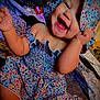 Milahni is registered to the contest to win money with this photo: baby, bed, blanket, child, clothing, colorful, cute, expression, face, floral_dress, hand, happy, indoors, infant, pattern, person, playful, portrait, skin, smiling
