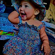Milahni is registered to the contest to win money with this photo: baby, child, smiling, happy, floral_dress, hat, indoors, sitting, cute, joyful, portrait, infant, colorful, clothing, person, playful, young_child, cheerful, face, cute_outfit
