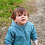toddler, child, blue_jacket, outdoor, gravel_path, curious, looking_up, short_hair, long_sleeves, nature, green_background, casual_clothing, small_hand, young_child, portrait, walking, daylight, cute, innocent, person