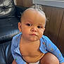 Jaden joined the competition — help win amazing prizes! baby, child, diaper, blue_clothing, curly_hair, indoor, leather_couch, window, wood_paneling, sitting, serious_expression, natural_light, hand, face, person, infant, cute, portrait, young_child, furniture