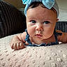 baby, blue_bow, headband, infant, face, eyes, blanket, couch, indoor, portrait, cute, child, skin, furniture, soft_texture, clothing, ruffles, expression, closeup, resting