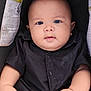 baby, child, infant, black_shirt, car_seat, warning_label, hands, face, eyes, skin, cute, chubby_cheeks, portrait, sitting, young_child, indoors, clothing, person, head, expression