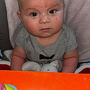 Naël a rejoint le concours — aidez-le/la à gagner de superbes lots ! baby, child, face, serious, plush_toy, cushion, blanket, high_chair, gray_clothing, indoor, toy, reflection, colorful, infant, person, cute, closeup, expression, sitting, young