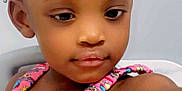 Essence joined the competition — help win amazing prizes! toddler, child, girl, pink_dress, bow, curly_hair, colorful, patterned_clothing, cute, portrait, indoor, young_child, skin, face, expression, reaching, sitting, bright_colors, head, closeup