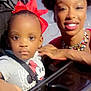 toddler, child, woman, stroller, red_bow, necklace, hoop_earrings, outdoor, evening, smile, face, person, clothing, hand, seatbelt, polka_dot, accessory, portrait, cute, family