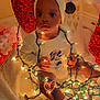 baby, child, christmas_lights, holiday, festive, bow_headband, minnie_mouse, cute, indoors, decorations, red, white, warm_lighting, sitting, cozy, string_lights, smiling, celebration, childrens_clothing, holiday_spirit
