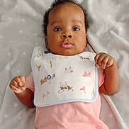 Elliott joined the competition — help win amazing prizes! baby, infant, child, face, eyes, bib, pink_shirt, blanket, animal_prints, cute, lying_down, soft_texture, indoors, portrait, young_child, hands, curly_hair, calm_expression, closeup, sleepwear