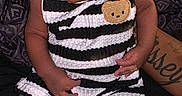 Emmanuel is registered to the contest to win money with this photo: baby, infant, striped_clothing, socks, teddy_bear_patch, tattoo, person, child, sitting, indoors, black_background, cute, portrait, young, small, cozy, casual, clothing, hand, skin