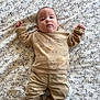 baby, infant, child, lying_down, blanket, patterned_blanket, clothing, pants, sweater, socks, face, head, cute, indoors, portrait, comfort, soft_texture, expression, young, human