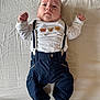 Mylan participe au concours pour gagner de l'argent avec cette photo : baby, infant, child, face, person, clothing, shirt, pants, suspenders, bed, blanket, white, blue, cute, lying_down, portrait, indoors, socks, floor, expression