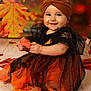 child, baby, toddler, orange_dress, headband, autumn, leaves, smile, portrait, studio, sitting, wooden_floor, holding_leaf, eyes, cheeks, cute, festive, black_tulle, background_bokeh, seasonal